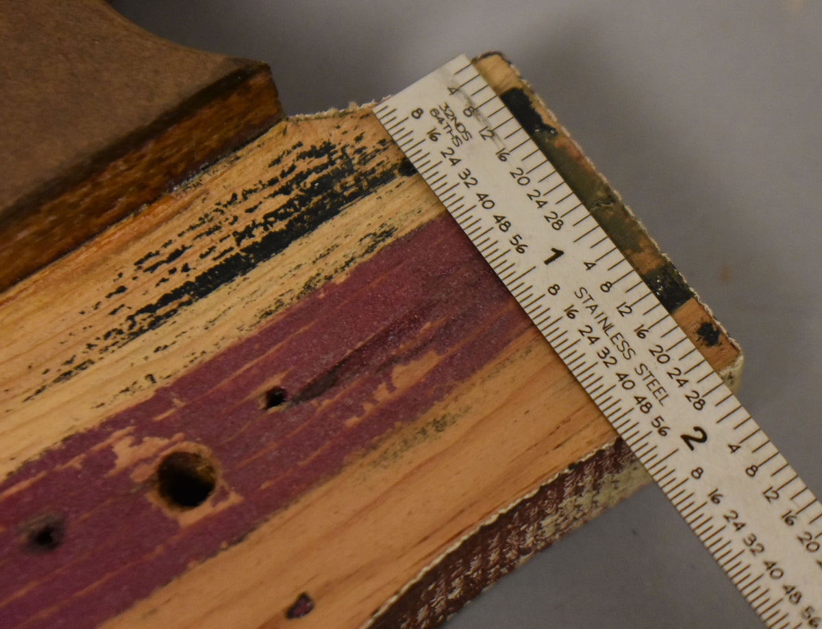 Close-up of the body's layered wood construction, showing black, natural, and purple-stained wood, with a ruler measuring the edge.