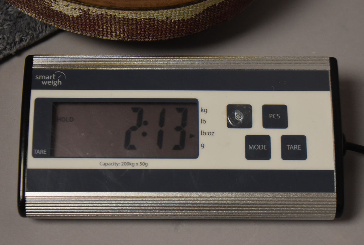 A digital scale displays "2.13" kg, with a guitar body's woven-patterned side partially visible above it.