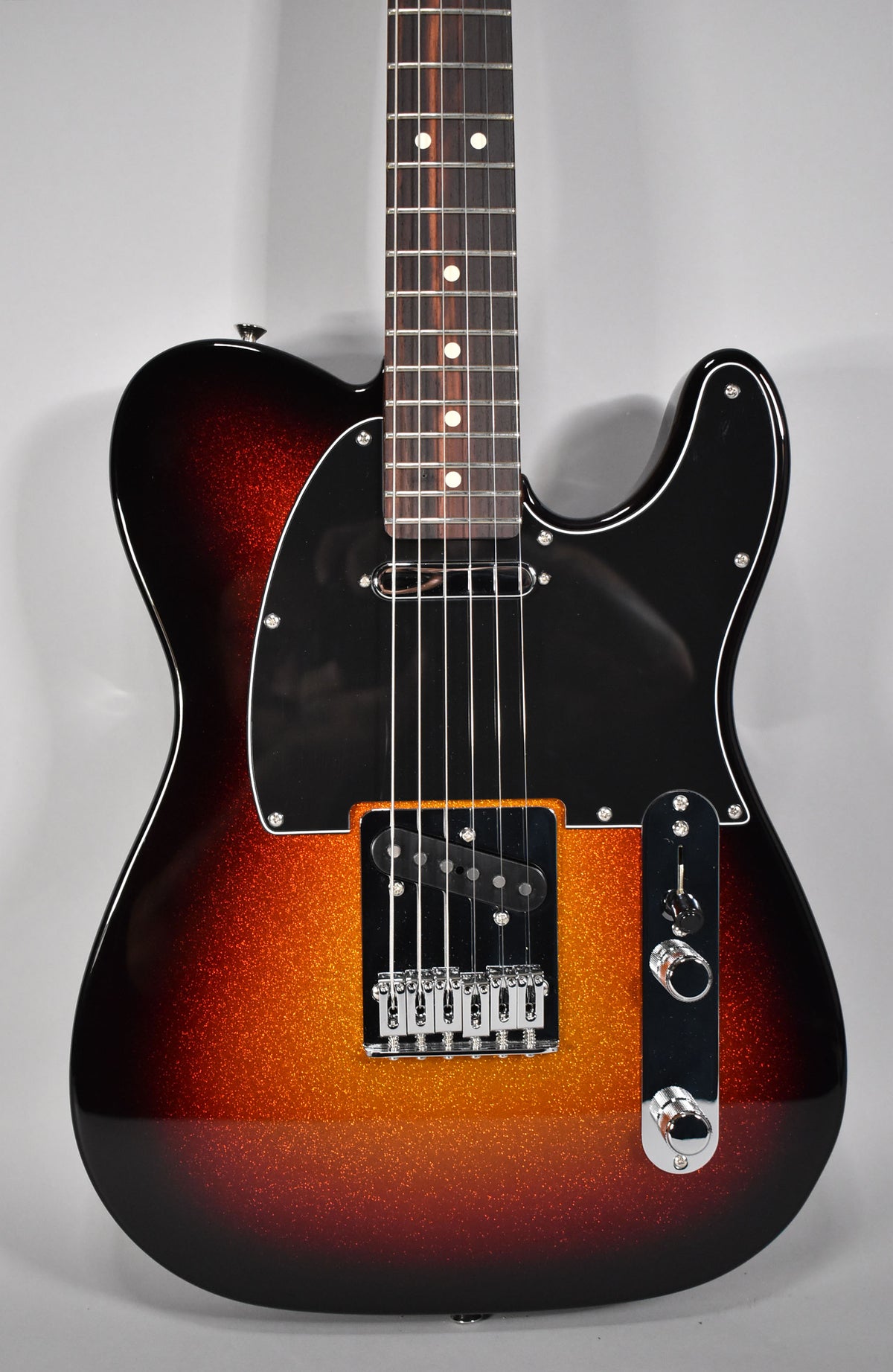The Telecaster's body, neck, and controls are shown from a slight angle, highlighting its sparkle sunburst finish and black pickguard.