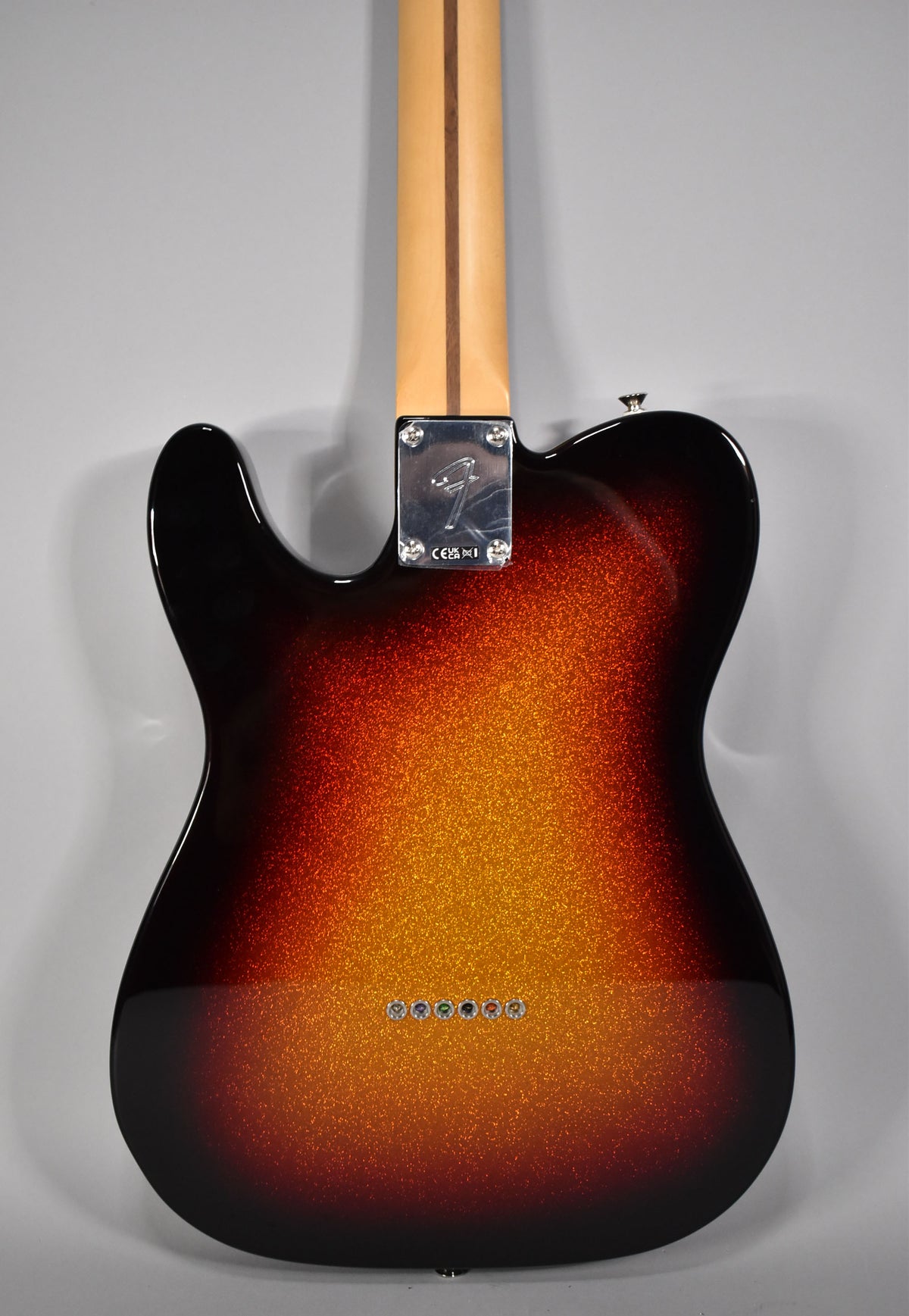 The back of a Telecaster, showing its 3-Color Sparkle Sunburst finish, chrome neck plate, and six string-through-body ferrules.
