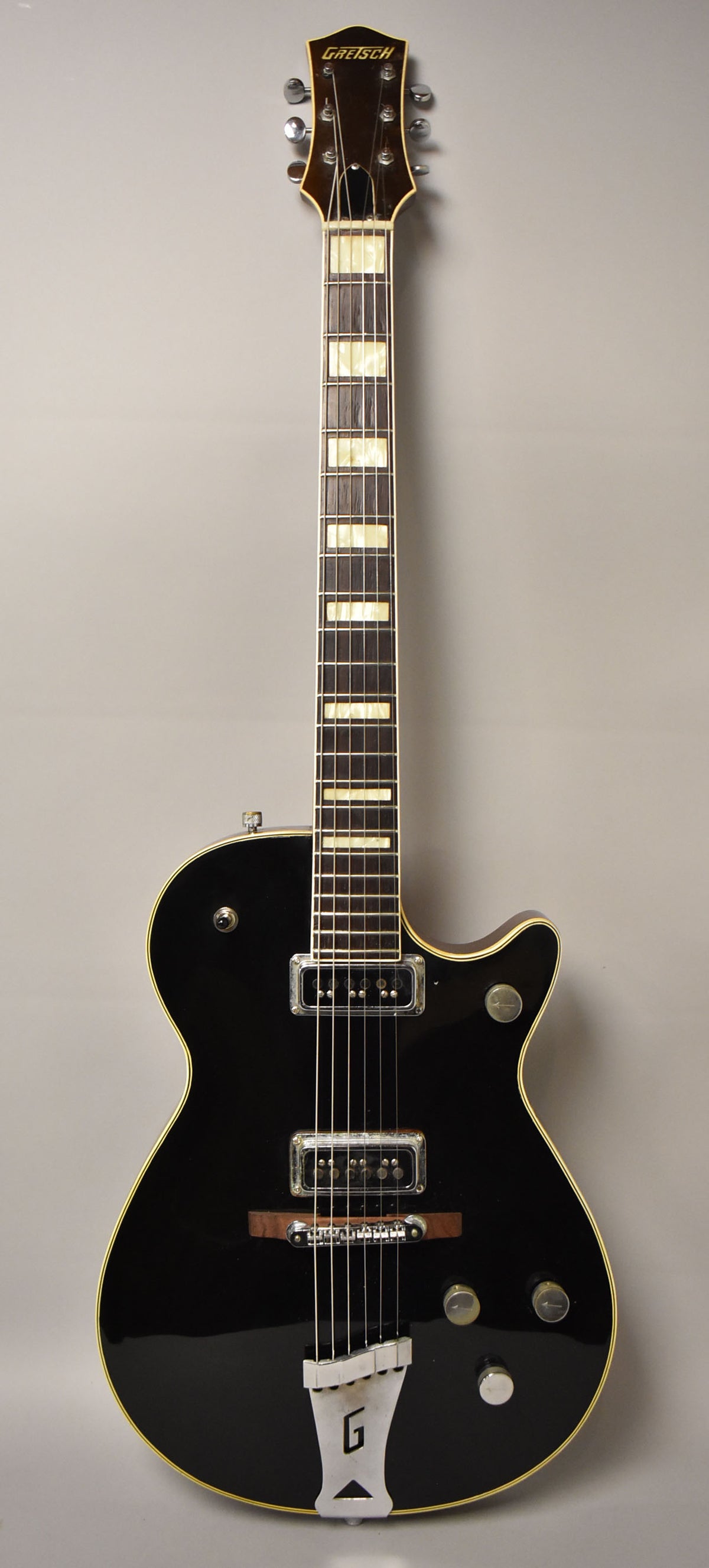 Full-length view of a black electric guitar with cream binding, two chrome pickups, and a G-branded tailpiece.