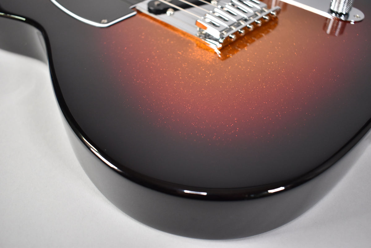Close-up of the guitar's lower body, showing the sparkle sunburst finish fading from black to orange, with a chrome bridge.
