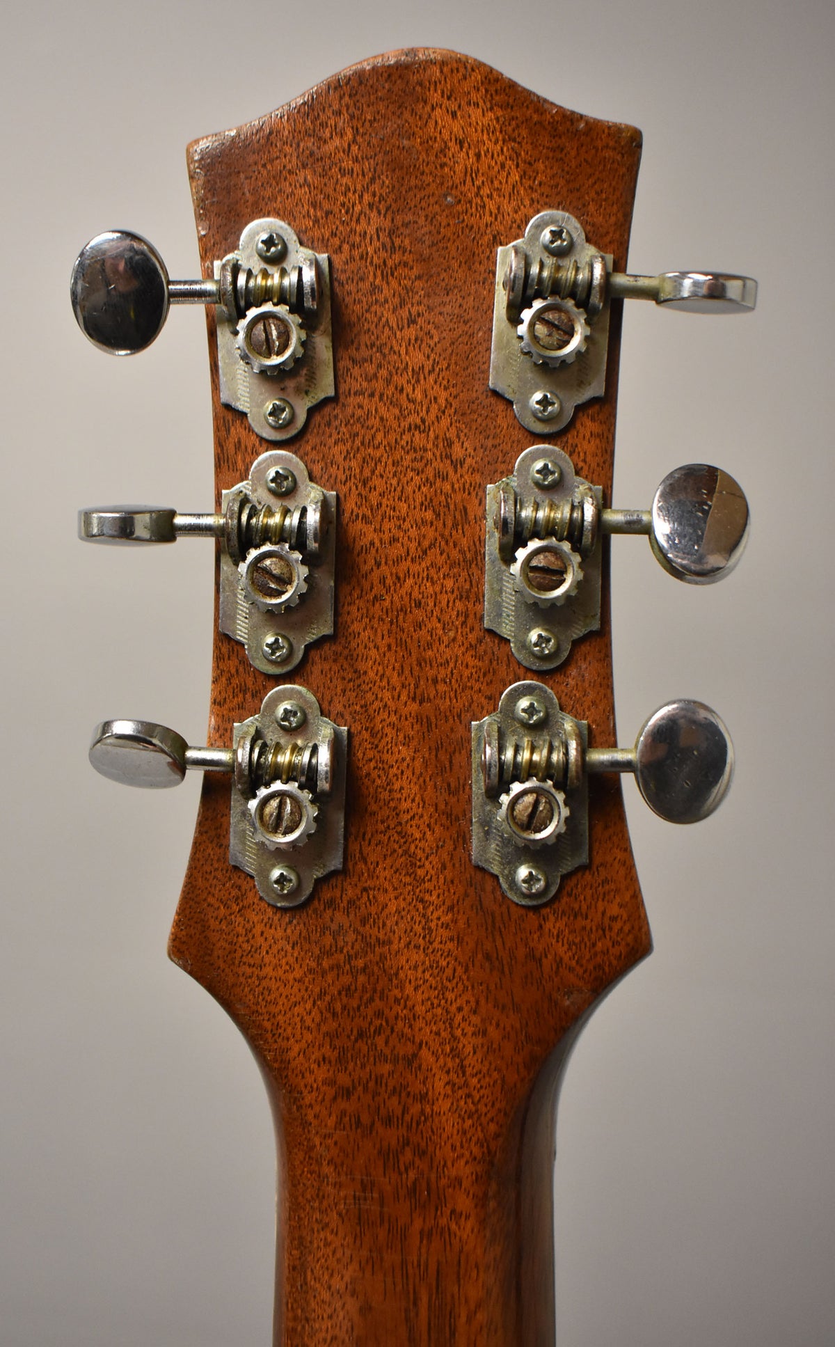 Rear view of the guitar's headstock and upper neck, showing six chrome tuners with visible wear and oxidation on the metal.