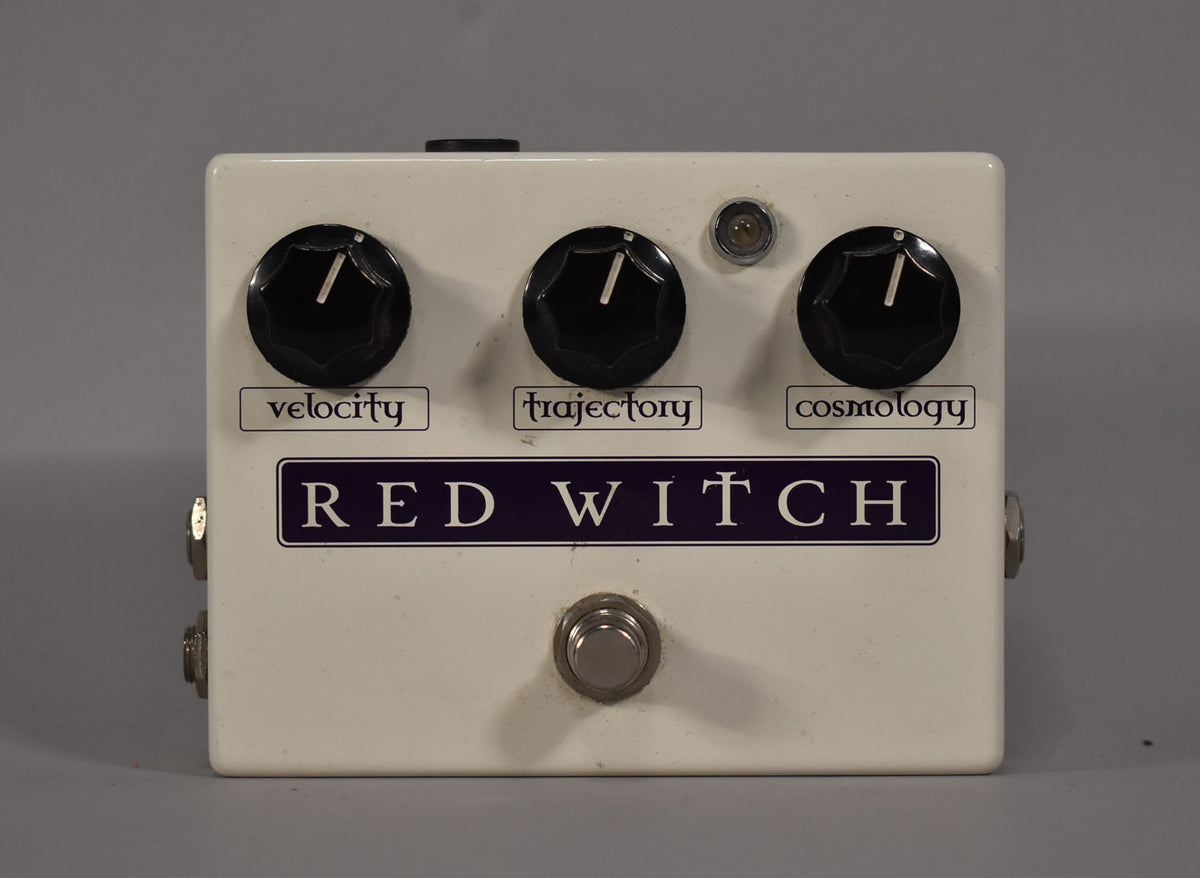 A white pedal with three black knobs labeled "velocity," "trajectory," and "cosmology," a small LED, and a footswitch.