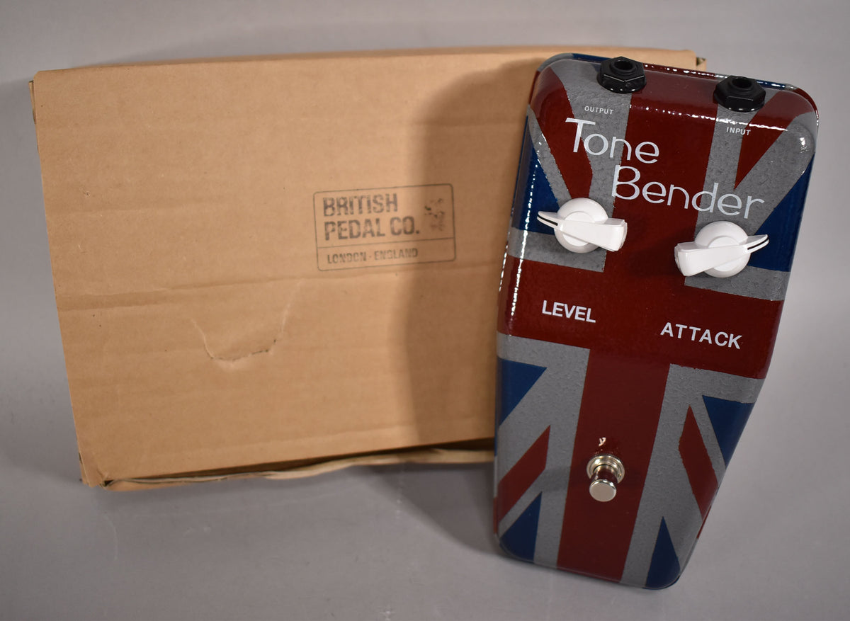 A Union Jack-emblazoned guitar pedal with two white knobs and a chrome footswitch, next to a plain cardboard box.