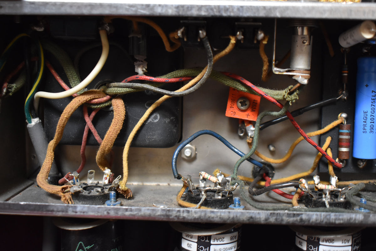 Close-up of the amplifier's internal wiring, showing colorful cloth-covered wires, resistors, and capacitors on a metal chassis.