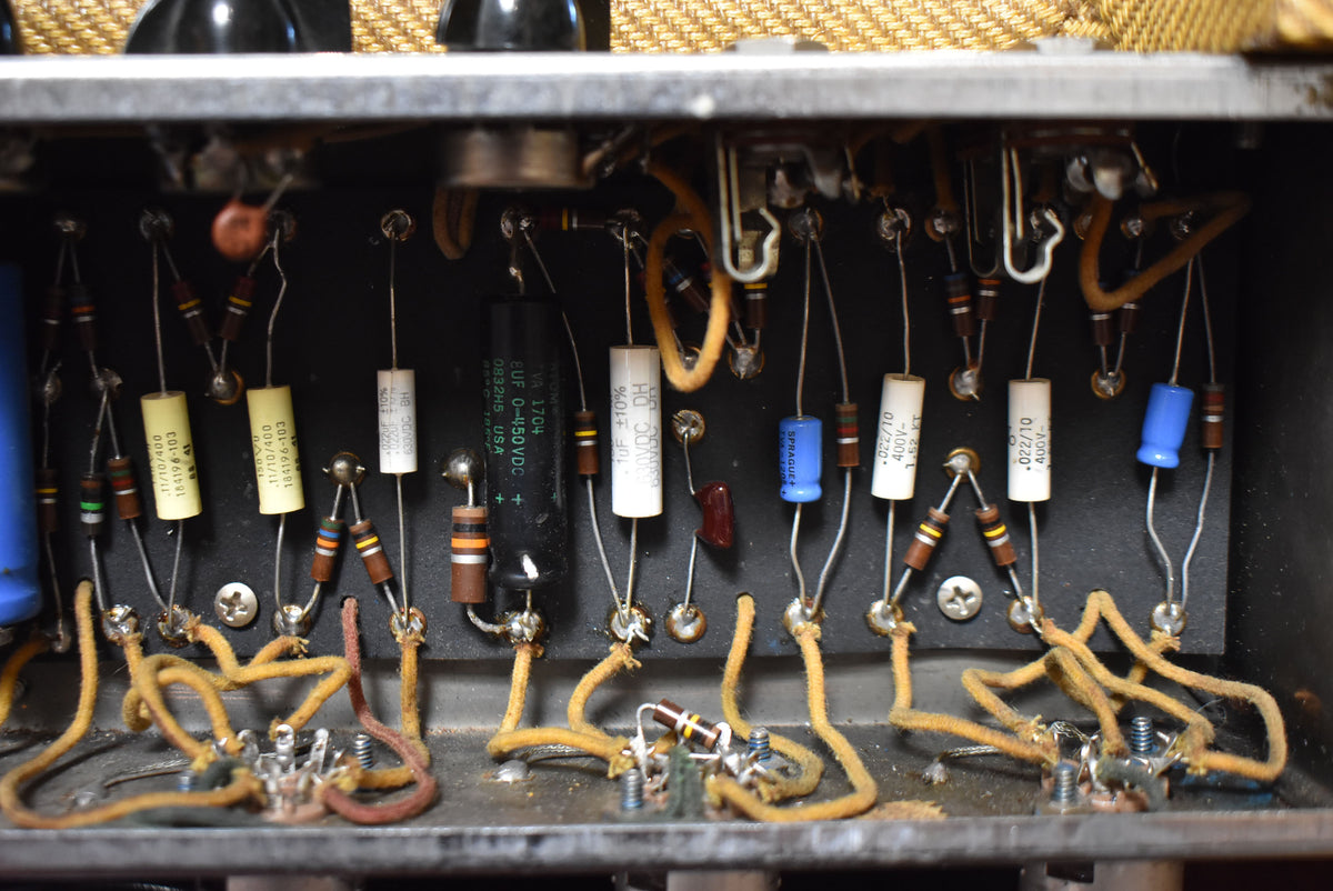 Close-up of the amp's internal wiring, showing various colorful capacitors, resistors, and aged yellow cloth-covered wires.
