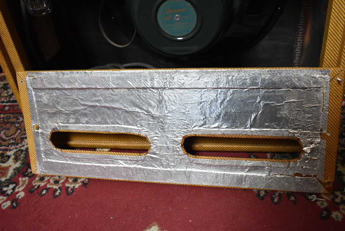 Top-down view of the amp's rear, showing the silver foil-lined chassis cover with two cutouts and the speaker visible inside.