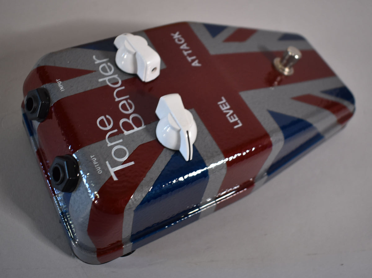 The pedal is angled, showing its glossy Union Jack finish, two white chicken-head knobs, a chrome footswitch, and two input jacks.