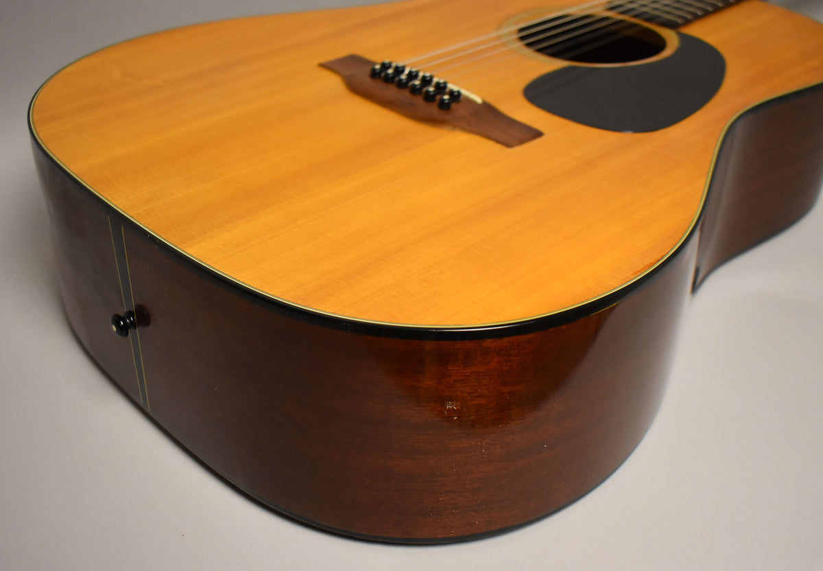 Close-up of the lower bout, showing the natural spruce top and dark mahogany sides with a small ding and a black end pin.
