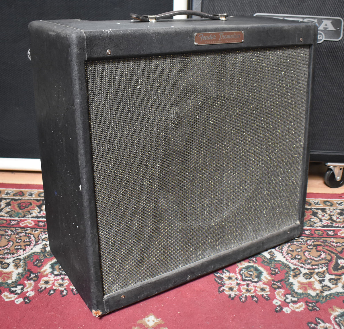Black tweed amp, angled view, shows a worn black leather handle, dark grille cloth, and scuffed bottom right corner.