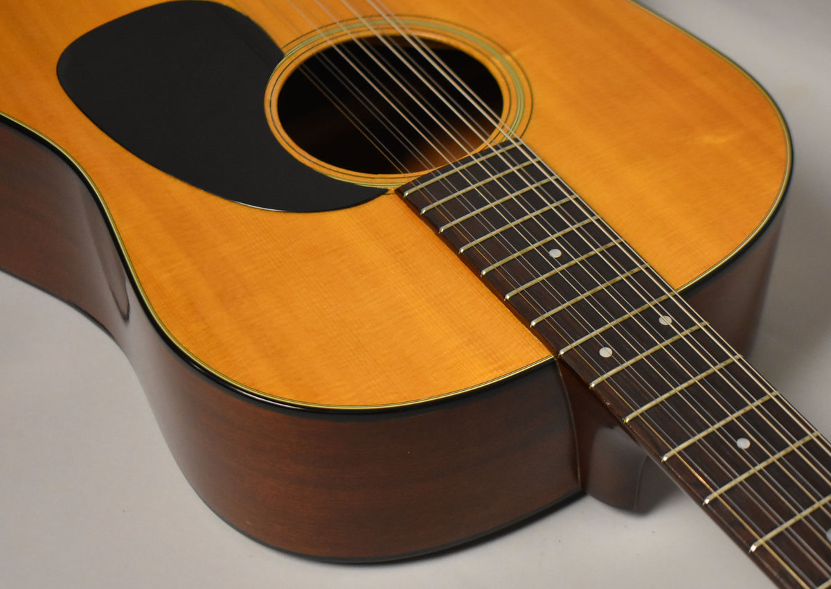 Close-up of the natural finish dreadnought's body and fretboard, showing the black pickguard, soundhole, and dot inlays.