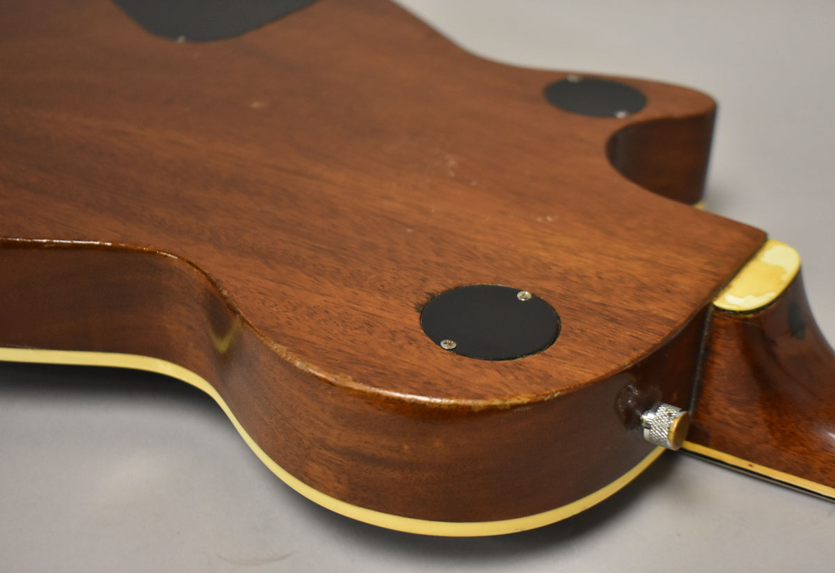 Back of the guitar body, showing the mahogany finish, cream binding, two black control cavity covers, and a strap button.