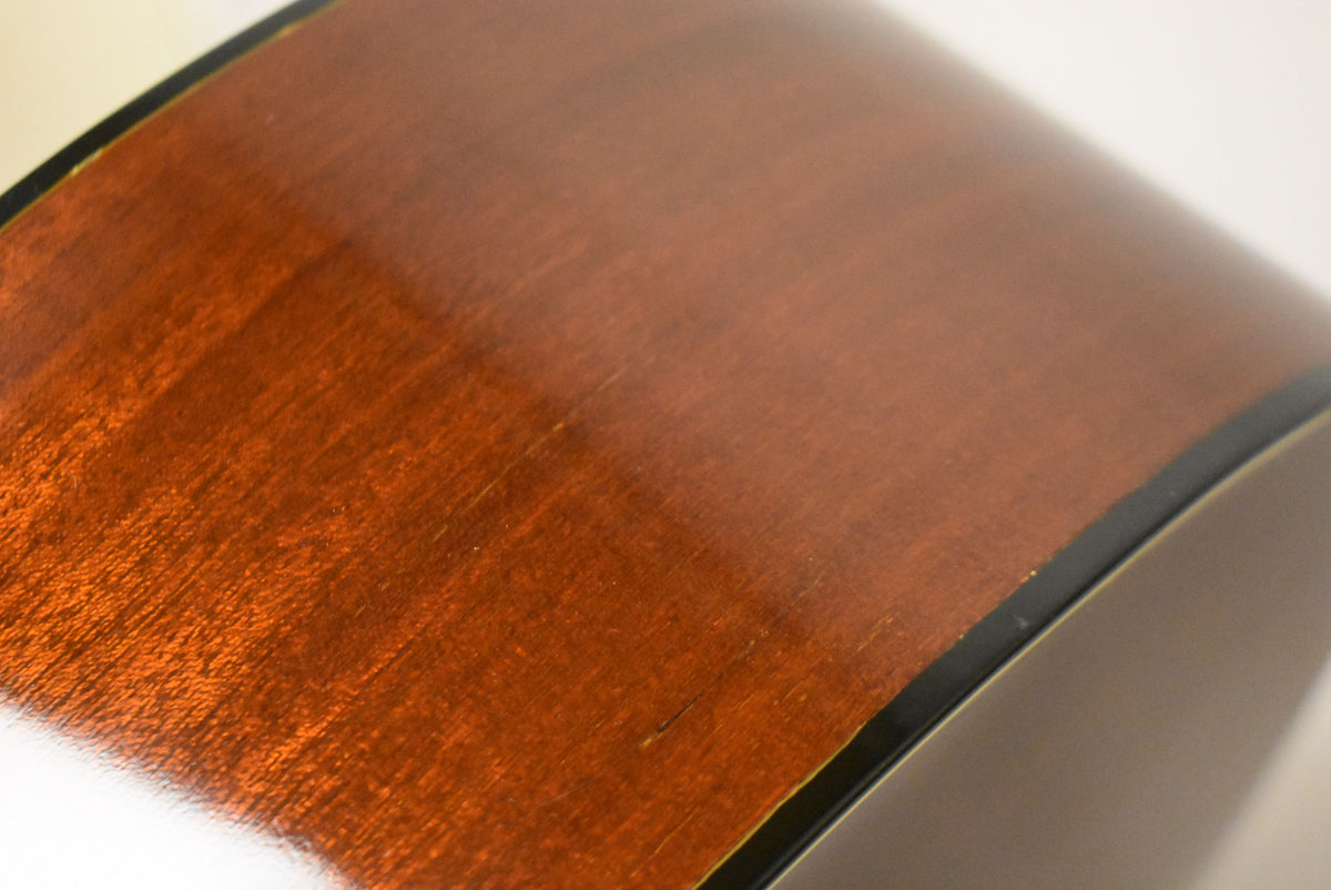 Close-up of the guitar's lower bout, showing the dark reddish-brown wood grain and several light scratches and a small ding.