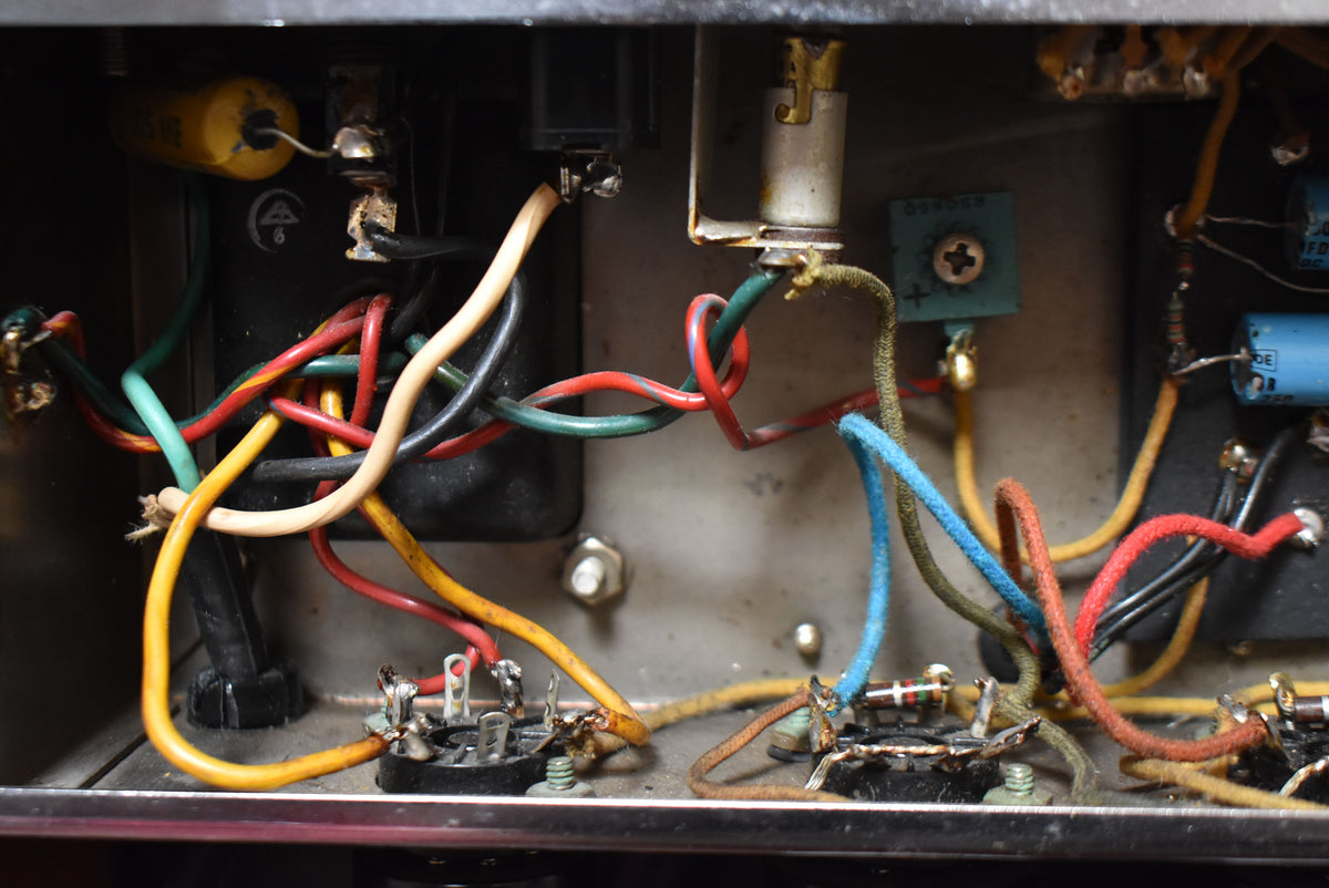 Close-up of the amp's interior, showing a tangle of colorful wires, capacitors, and tube sockets with visible dust and wear.