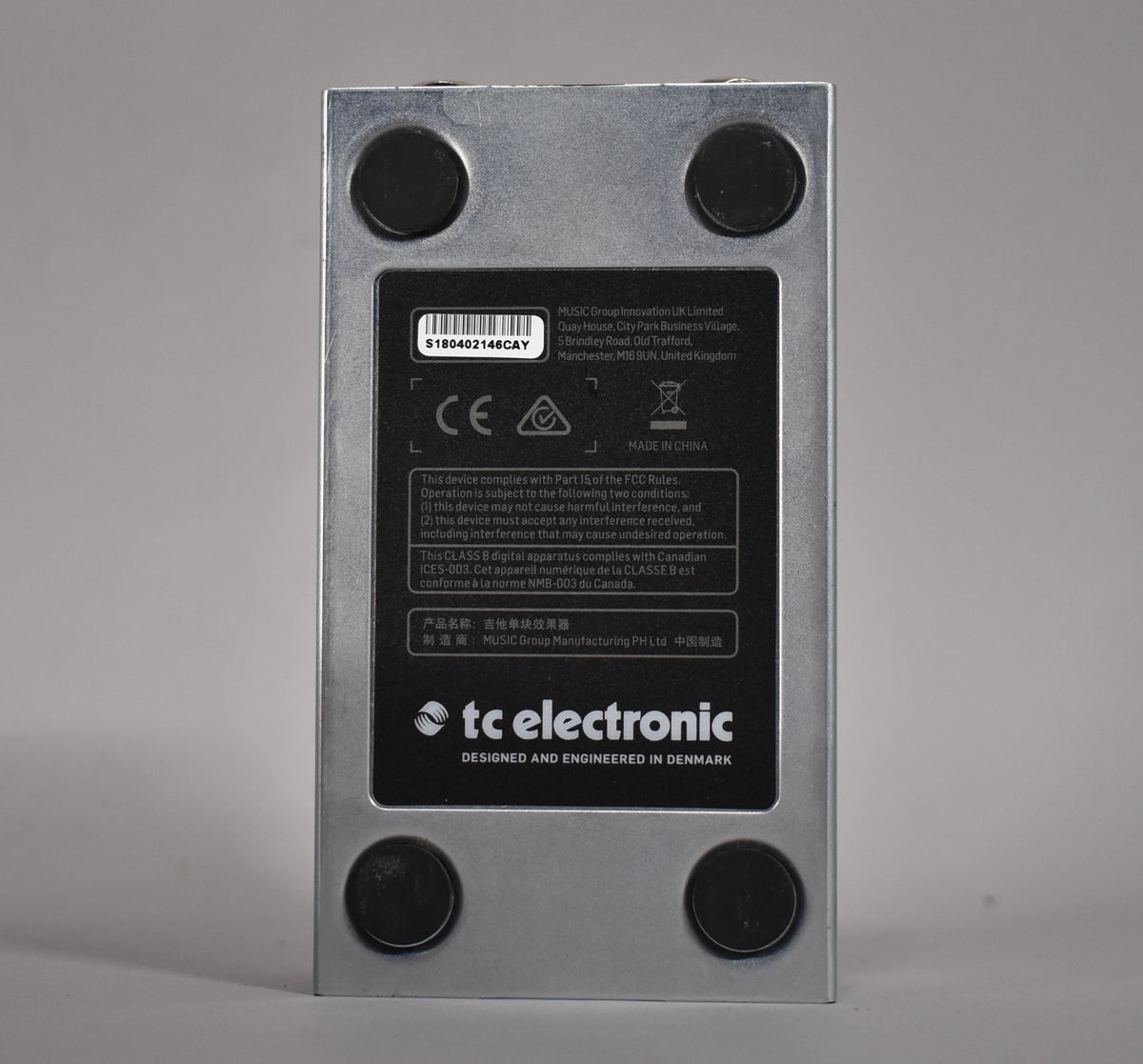 The pedal's brushed silver bottom plate is visible, with four black rubber feet and a large black label.