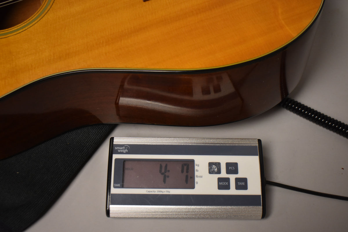 The guitar's lower bout and waist are shown from above, with a digital scale displaying "4:17" in pounds and ounces.