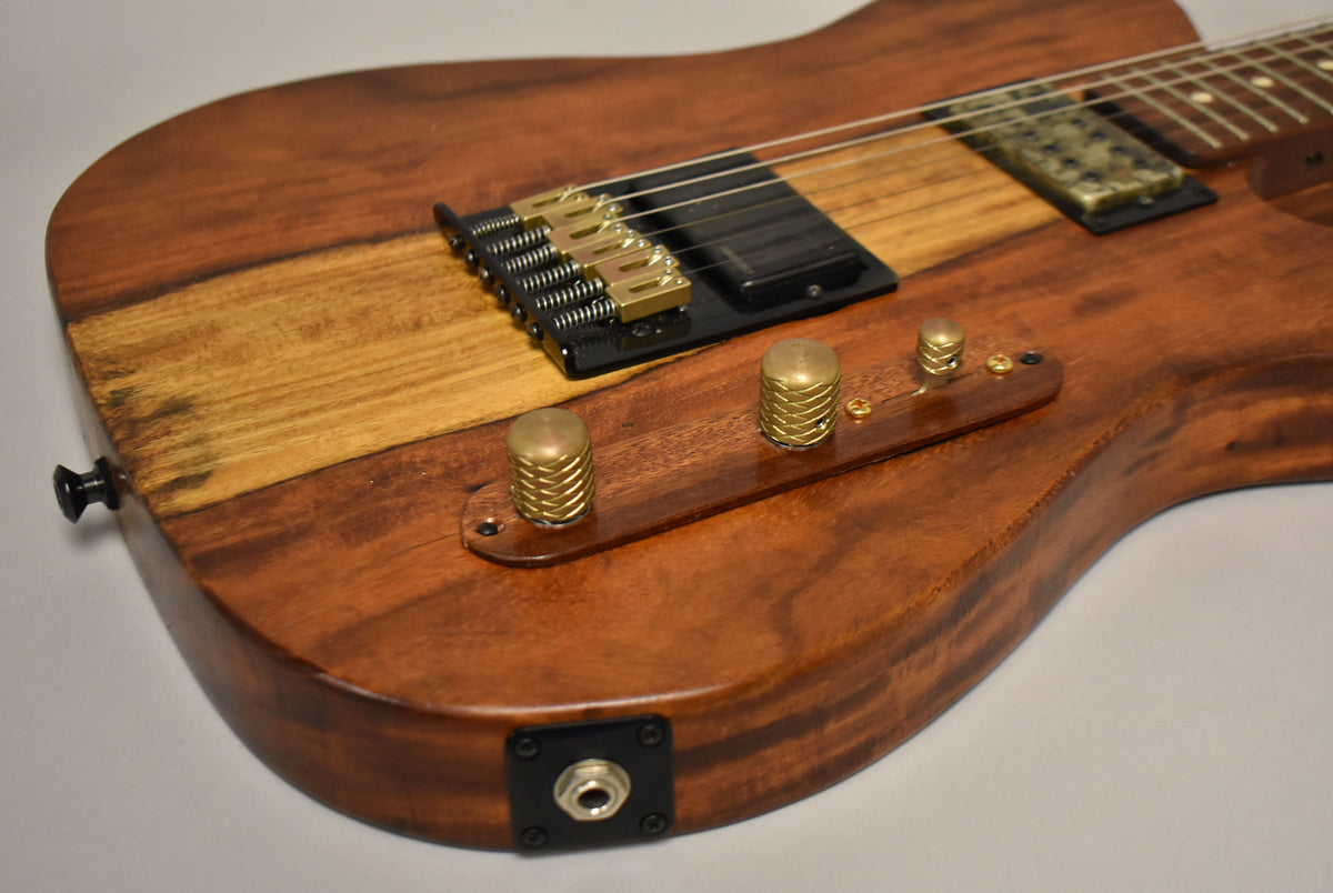 Close-up of the guitar's lower body, showing the natural wood grain, brass hardware, and black output jack.
