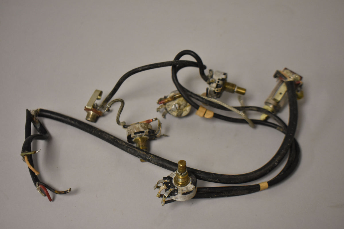 A tangle of black wires with exposed ends, connected to several tarnished metal potentiometers and jacks, showing heavy wear.