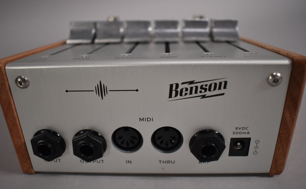 The pedal's rear panel, framed from above, shows a brushed silver finish with wood sides, featuring various black input/output jacks.
