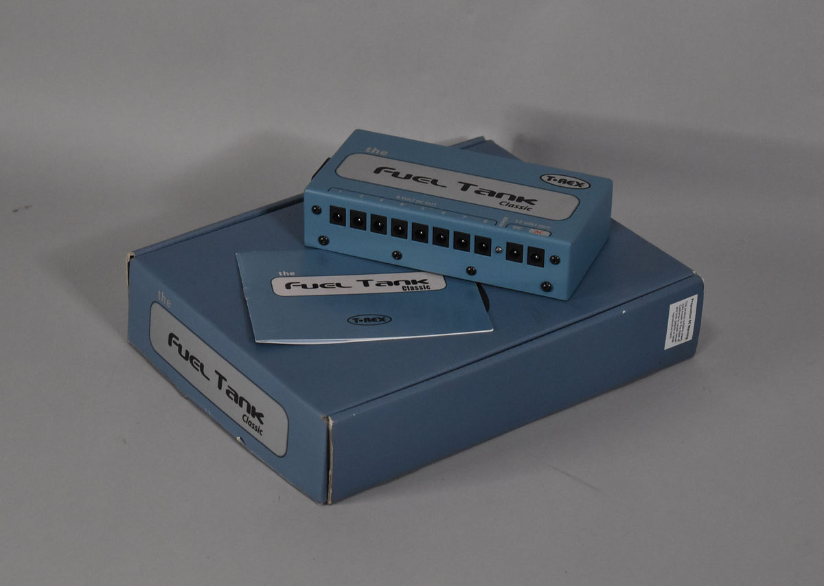 The light blue power supply with ten black output jacks sits atop its matching box and instruction manual.