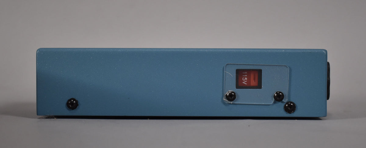 The blue-grey power supply is viewed from the side, showing a red 115V switch under a clear plastic cover.