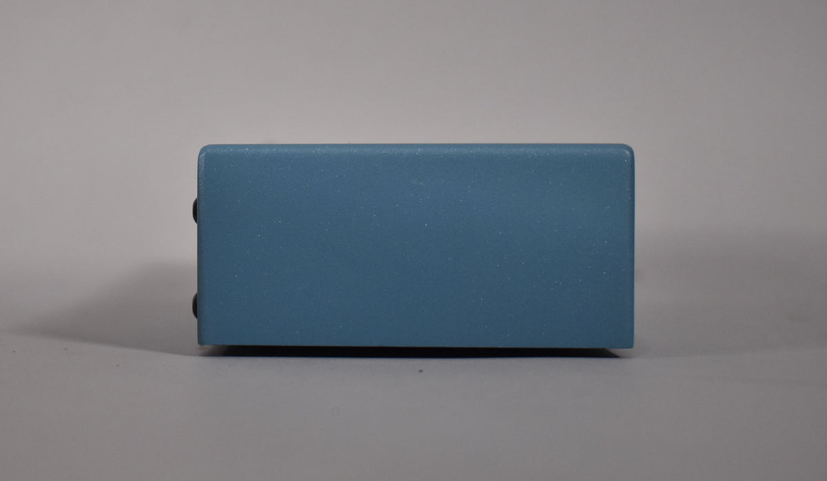 The power supply is a rectangular, textured blue box, viewed from the front, with two black ports visible on the left side.
