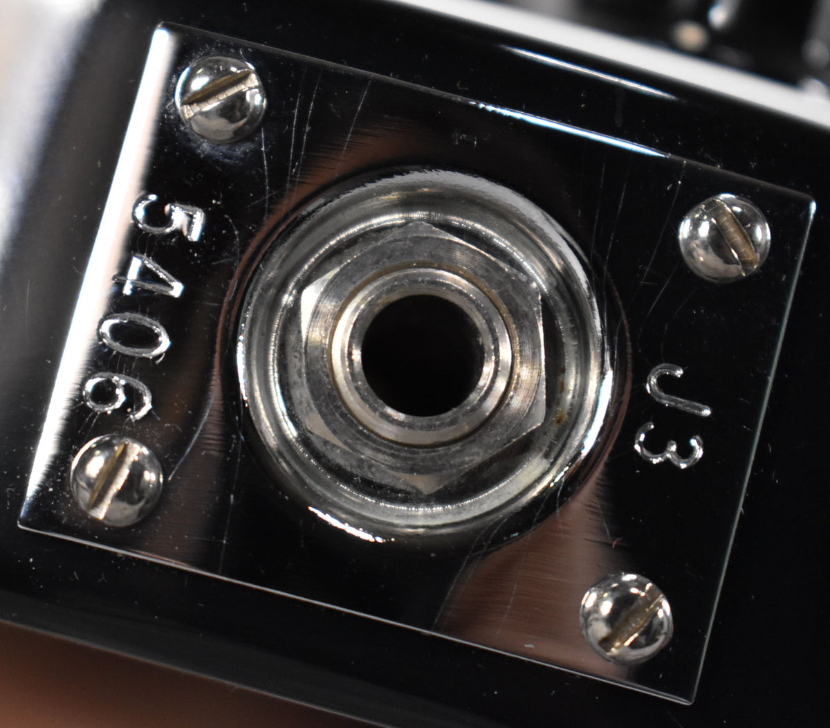 Close-up of the chrome output jack plate, secured by four screws, showing light scratches and the etched numbers "54066" and "J3".