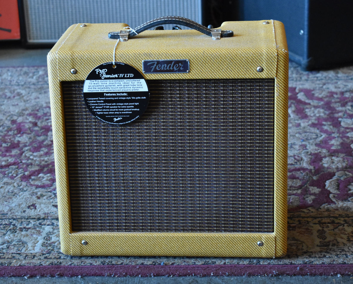 Front view of a lacquered tweed combo amp with a dark brown grille cloth, black leather handle, and a black hang tag.