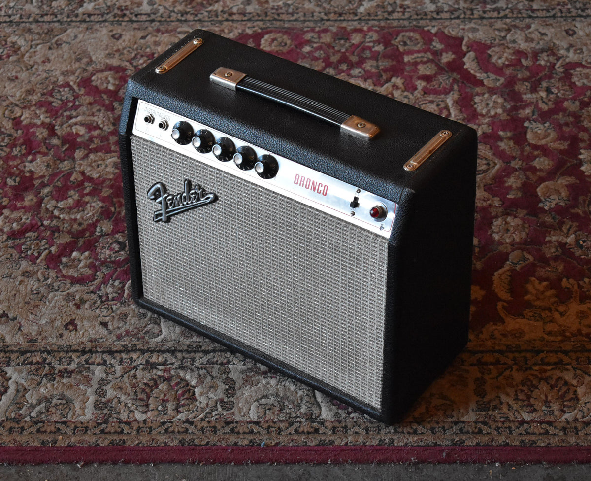 Black tolex combo amp with silver grille cloth, chrome control panel, 5 black knobs, and a red pilot light, viewed from above.