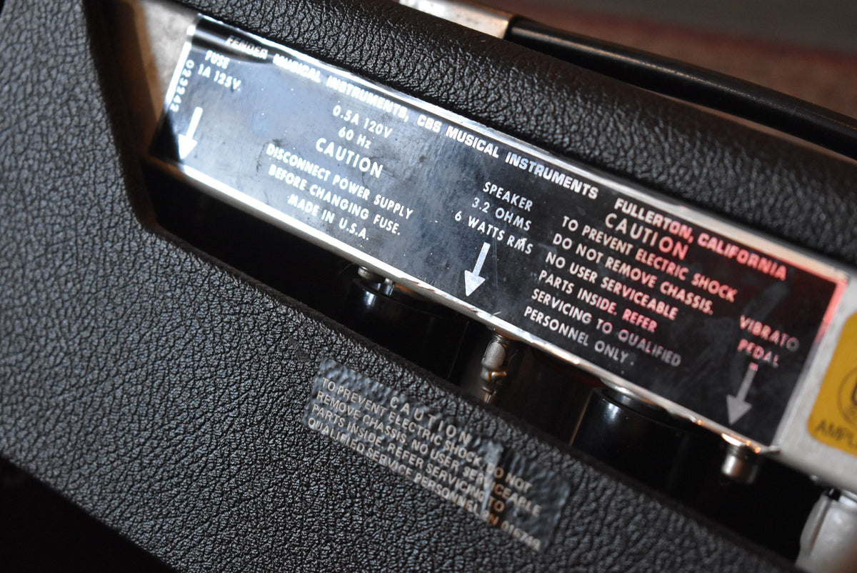 Close-up of the amp's black textured vinyl covering and a silver metal panel with black text, including a red "CAUTION" warning.
