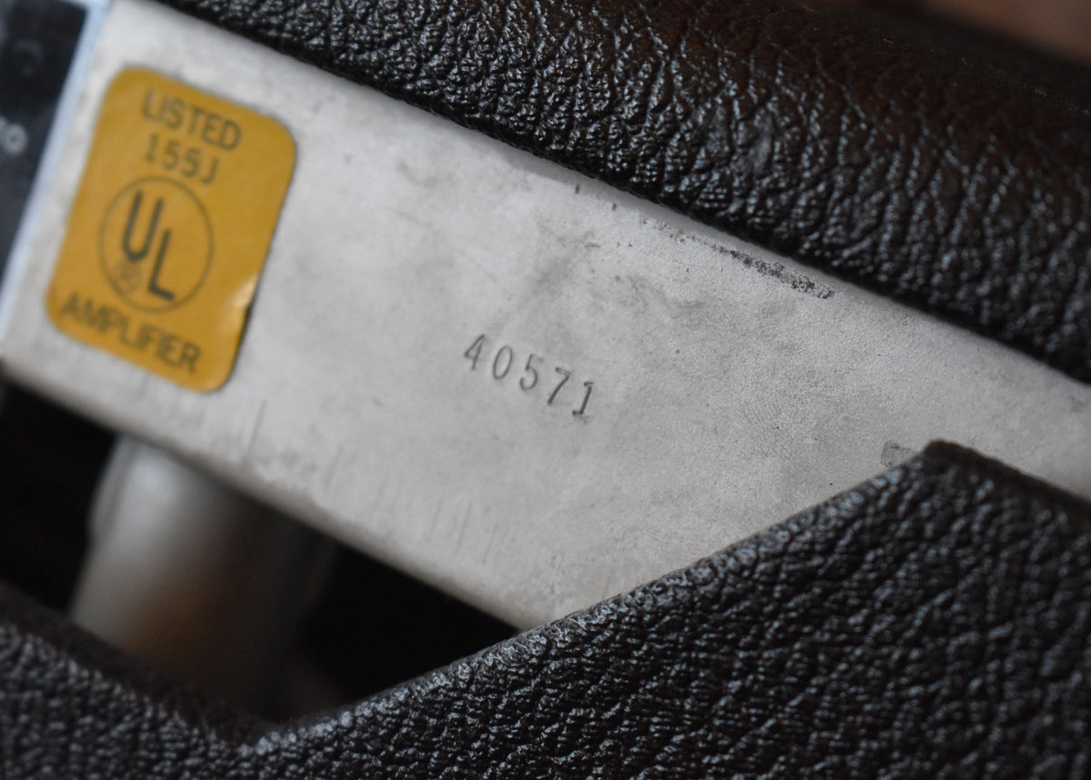 Close-up of the amp's metal chassis, showing a yellow UL sticker and the stamped serial number "40571" against dark tolex.