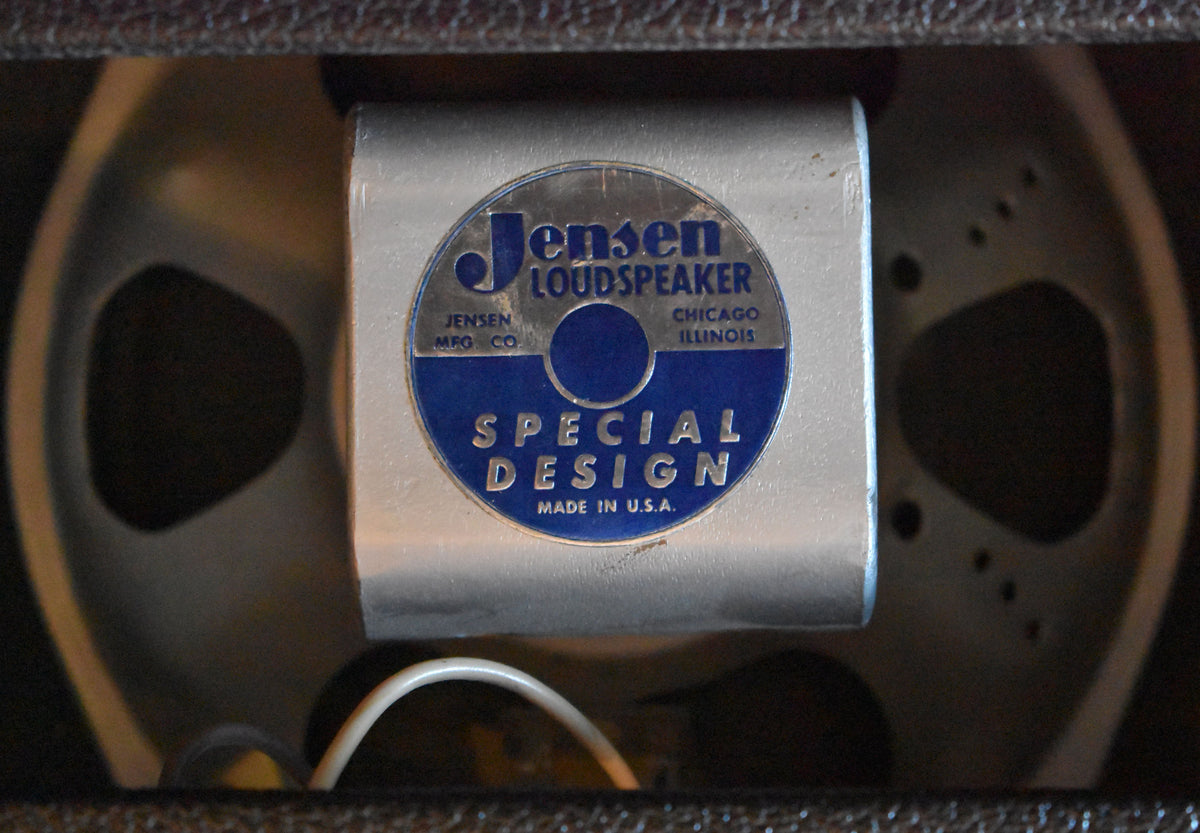 Close-up of the speaker's silver-toned magnet with a blue and silver label, showing some wear and a white wire below.