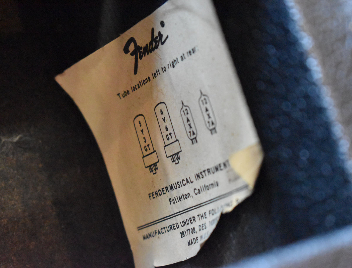 Close-up of the amp's faded, curled tube chart label, showing tube diagrams and text on a dark, textured background.