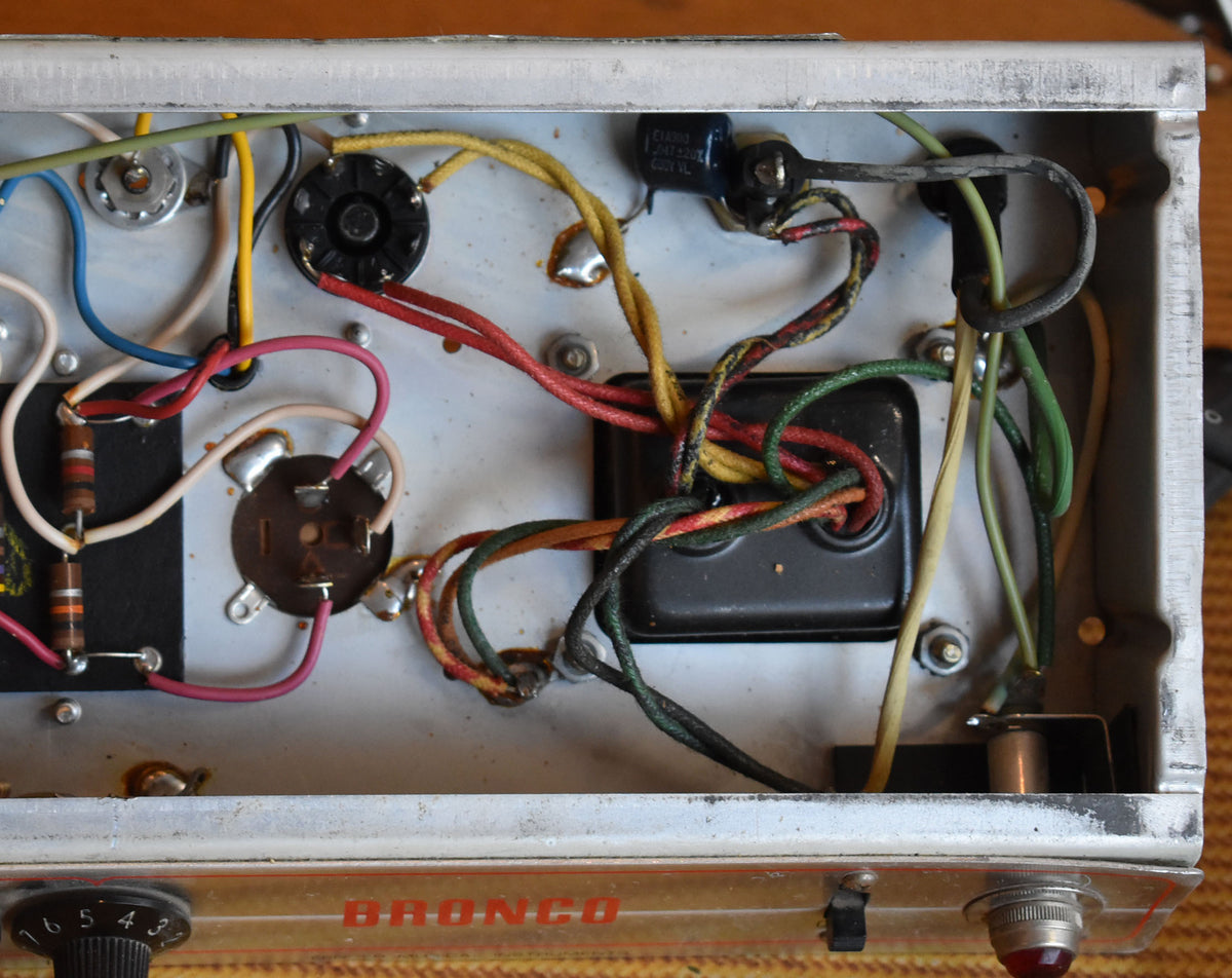 Top-down view of the amp chassis, revealing a tangle of colorful wires, tube sockets, resistors, and a black transformer.
