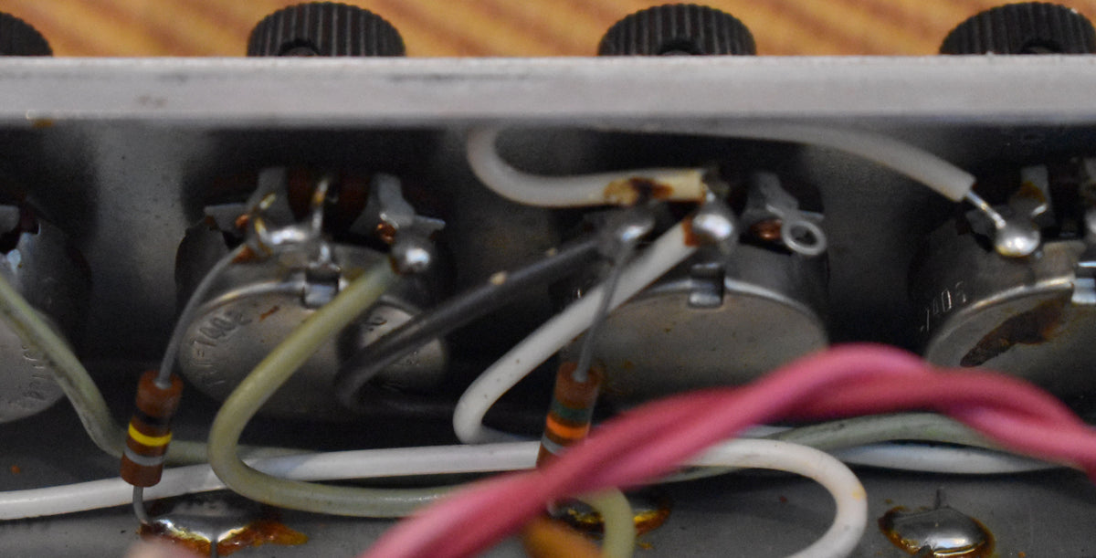 Close-up of the amp's internal wiring, showing several silver potentiometers, resistors, and colorful wires with some visible corrosion.