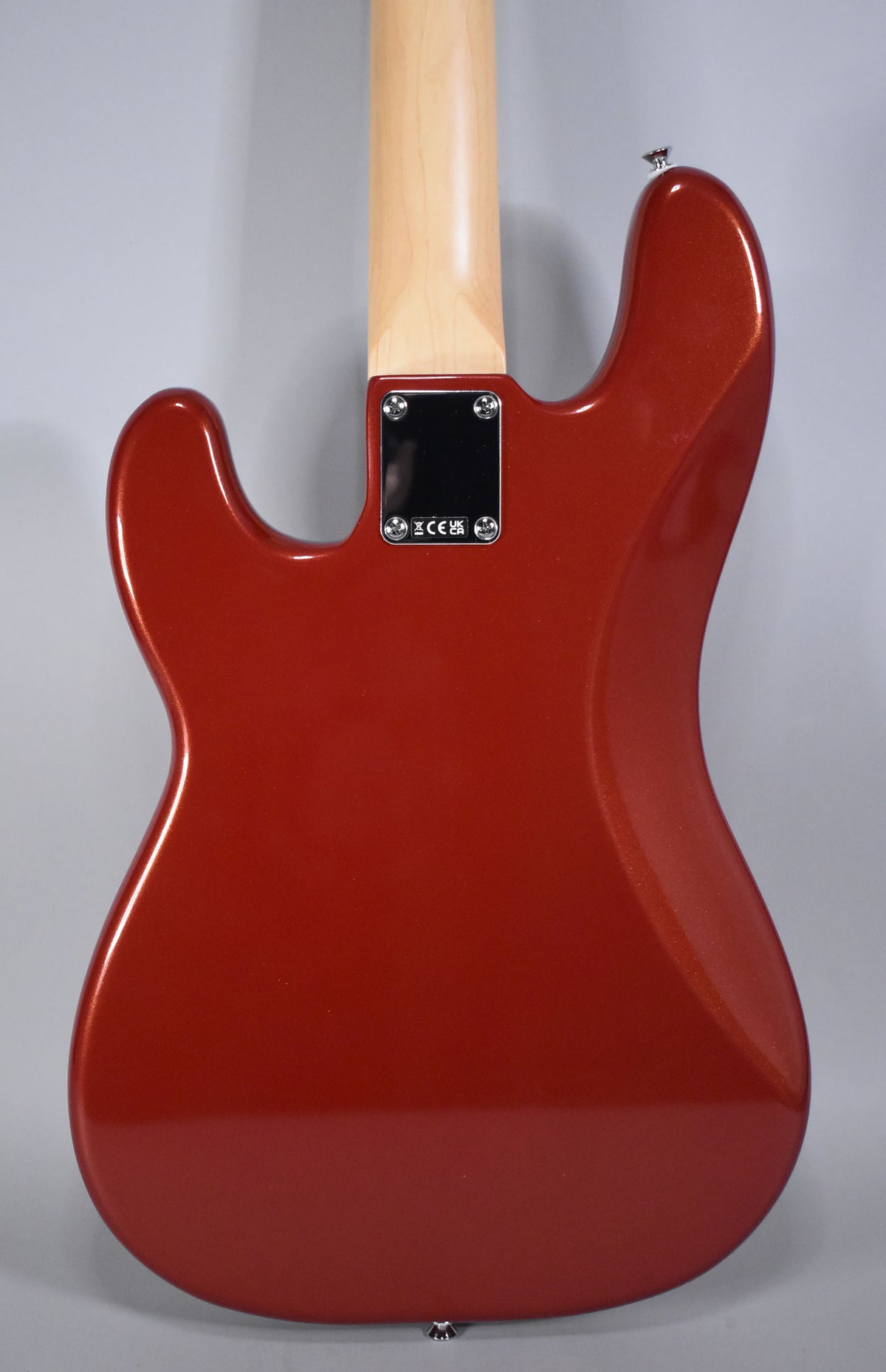The bass guitar's back is shown, featuring a metallic Candy Cola finish, a light wood neck, and a chrome neck plate.