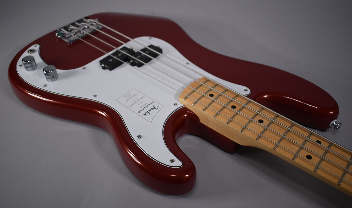 A Candy Cola Precision Bass with a white pickguard and maple fretboard, viewed from above, angled right.