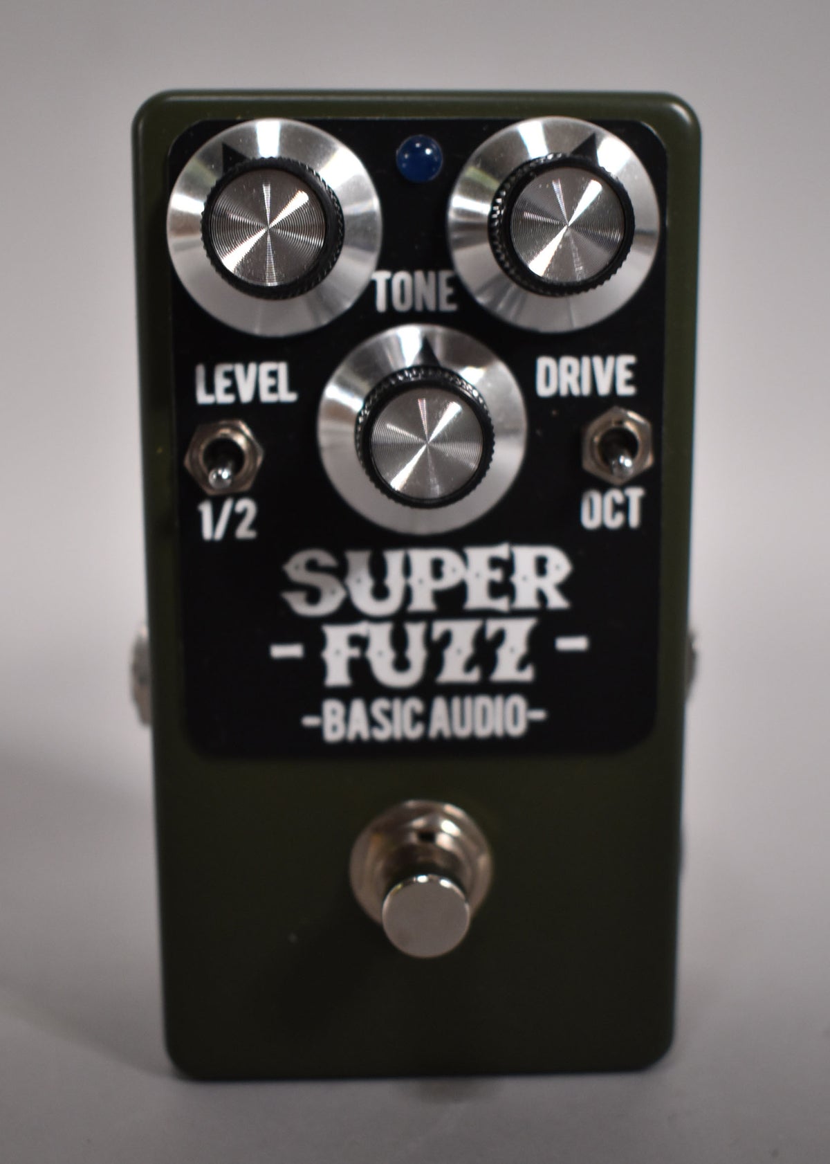 A dark green Basic Audio Super Fuzz effect pedal with three silver knobs, a blue LED, and a footswitch.