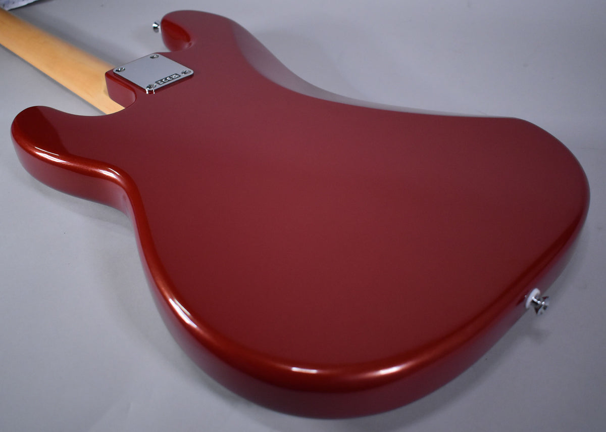 The back of a Candy Cola red bass guitar, angled to show the chrome neck plate and output jack.