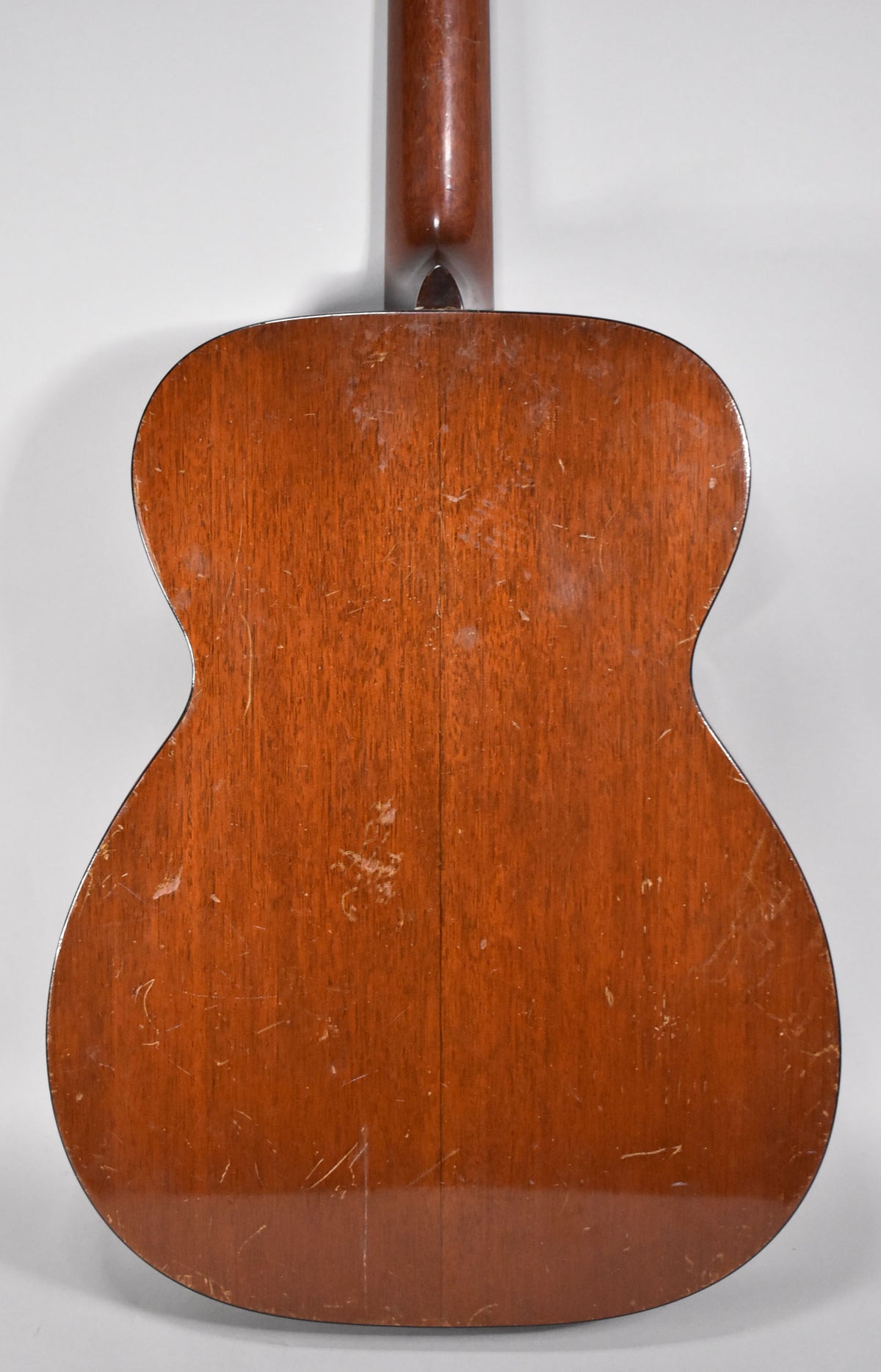 The guitar's back and neck are visible, showing a natural finish with extensive wear, scratches, and finish checking.