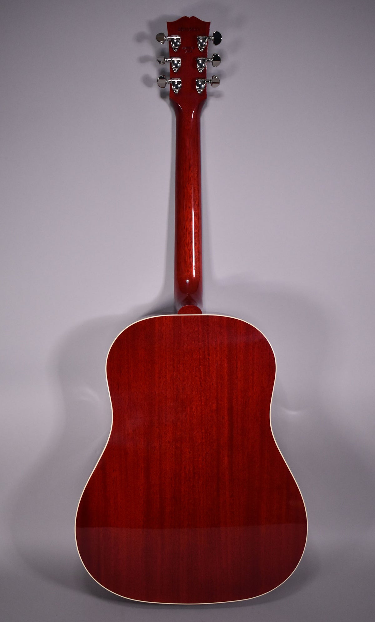 The full back of the cherry-finished acoustic guitar is shown, with a glossy, deep red body and neck, and chrome tuners.