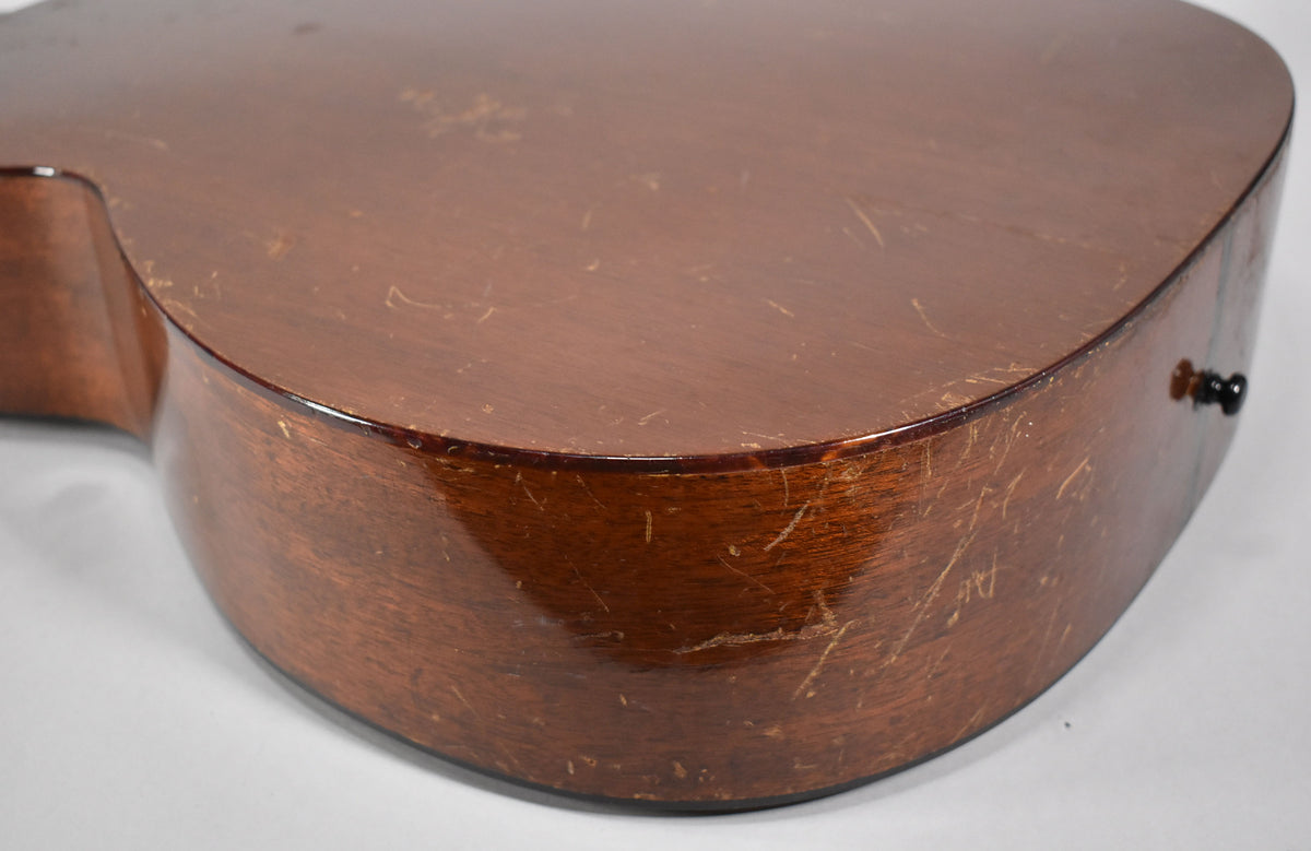 The lower bout of the acoustic guitar, showing the natural finish with extensive scratches, dings, and finish checking.
