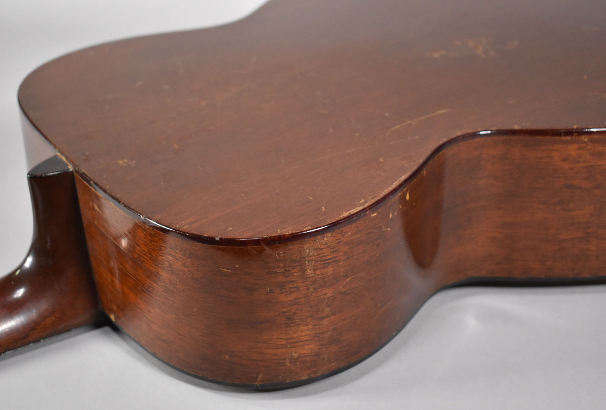 The lower bout of the guitar's dark brown body, showing wear, scratches, and finish checking on the back and side.