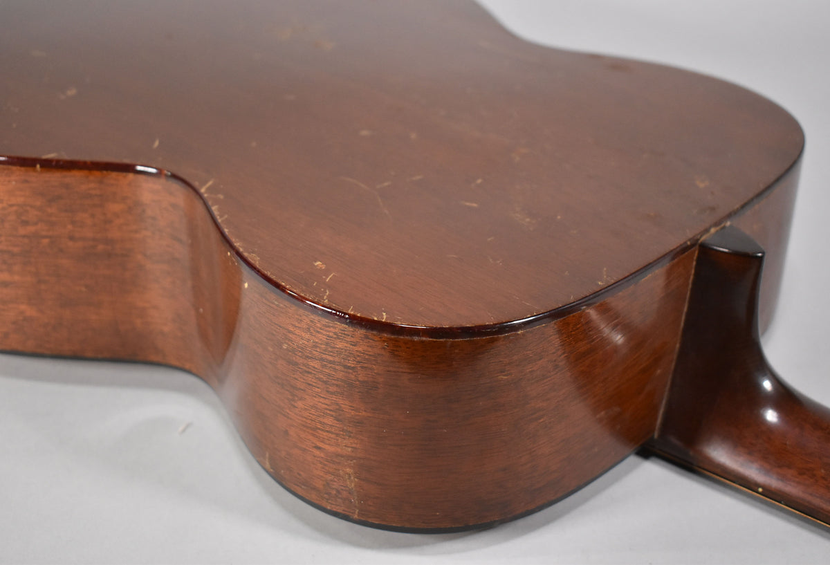 The lower bout and waist of the guitar's dark brown body, showing significant finish wear, scratches, and dings.