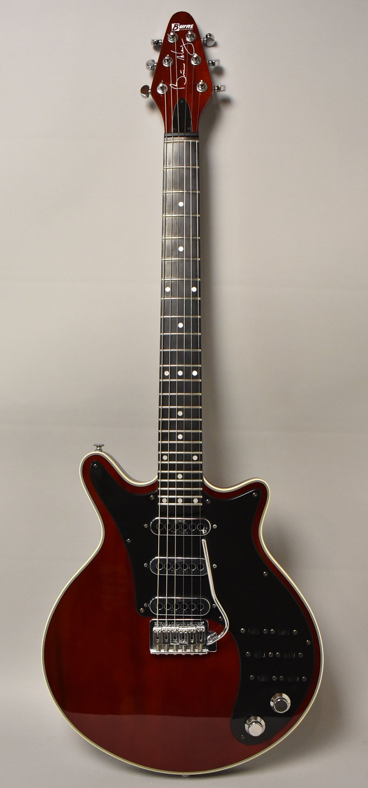 Full-length view of a cherry red electric guitar with a black pickguard, three pickups, and six control switches.