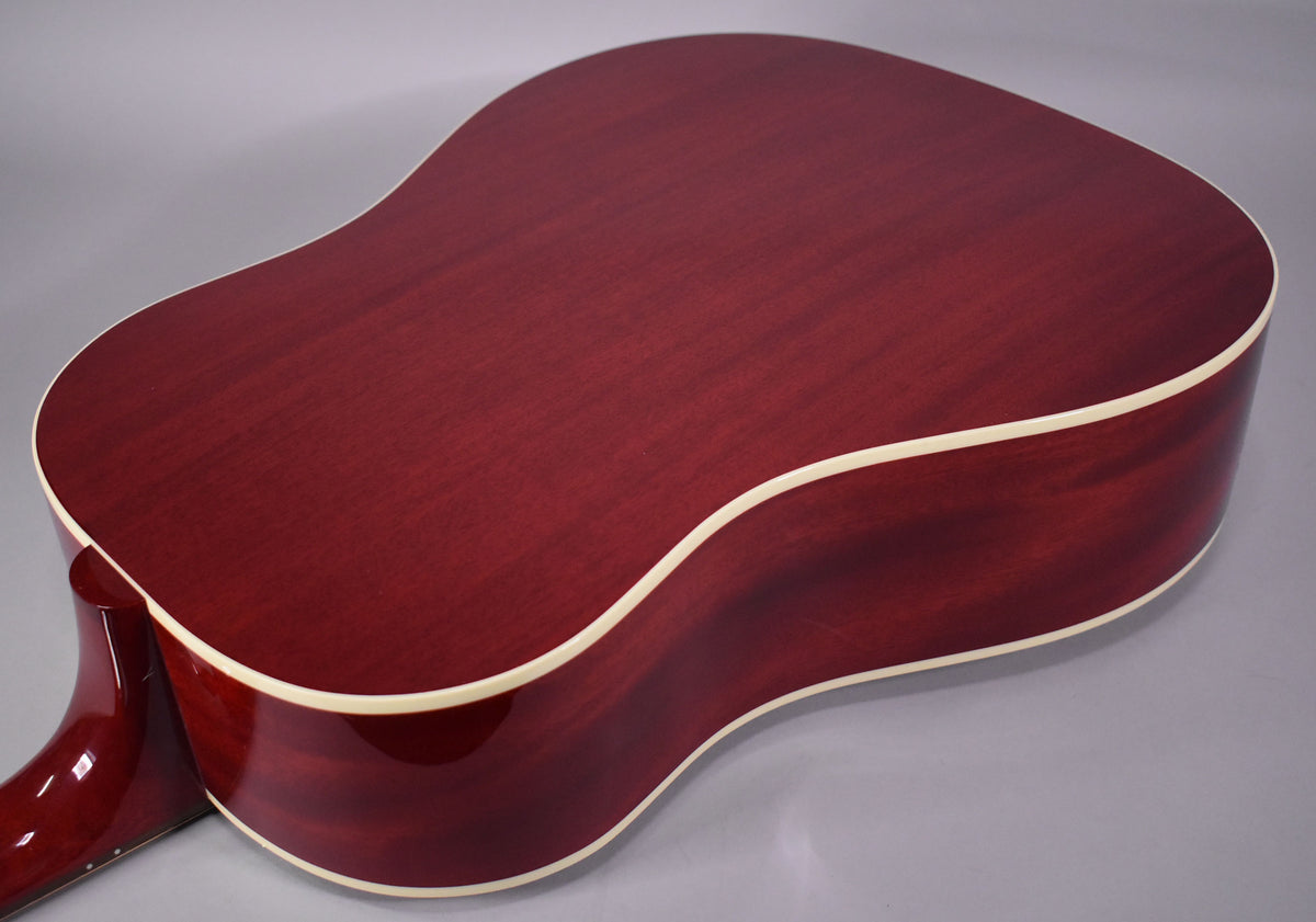 The back of the cherry red acoustic guitar, with visible wood grain, is angled from the upper left to the lower right, showing cream binding.