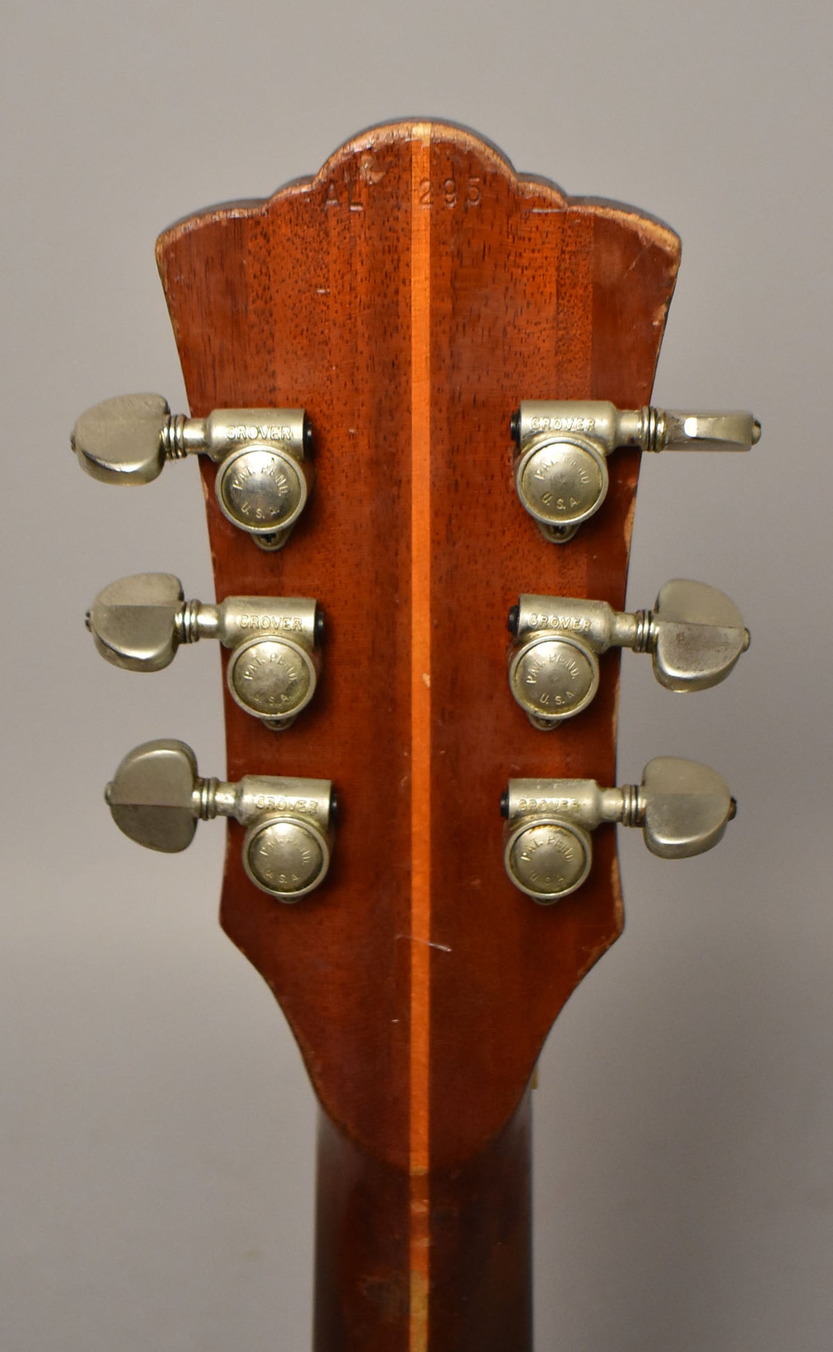 The back of the headstock and top of the neck, showing six nickel tuners, a dark wood finish, and visible wear along the edges.