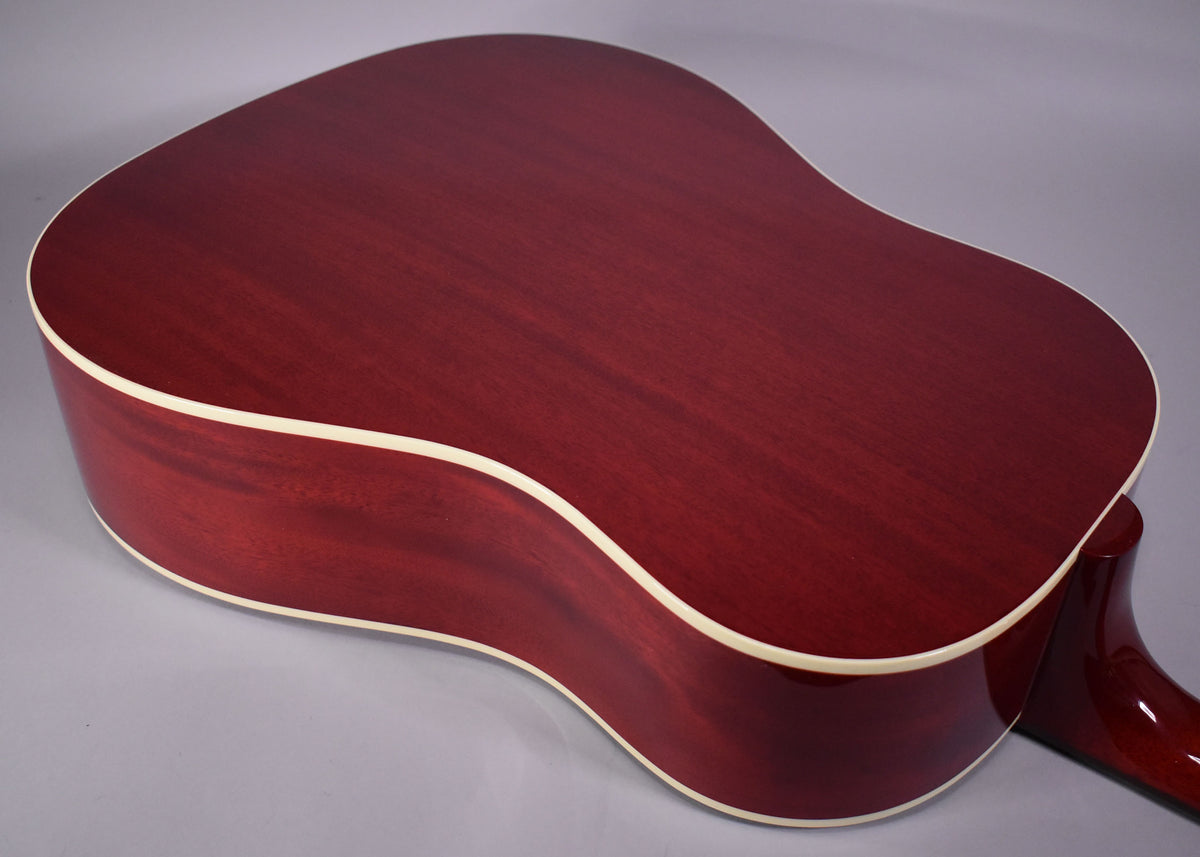 The back of the cherry-finished acoustic guitar, showing the body's grain and cream binding, with a glimpse of the neck heel.