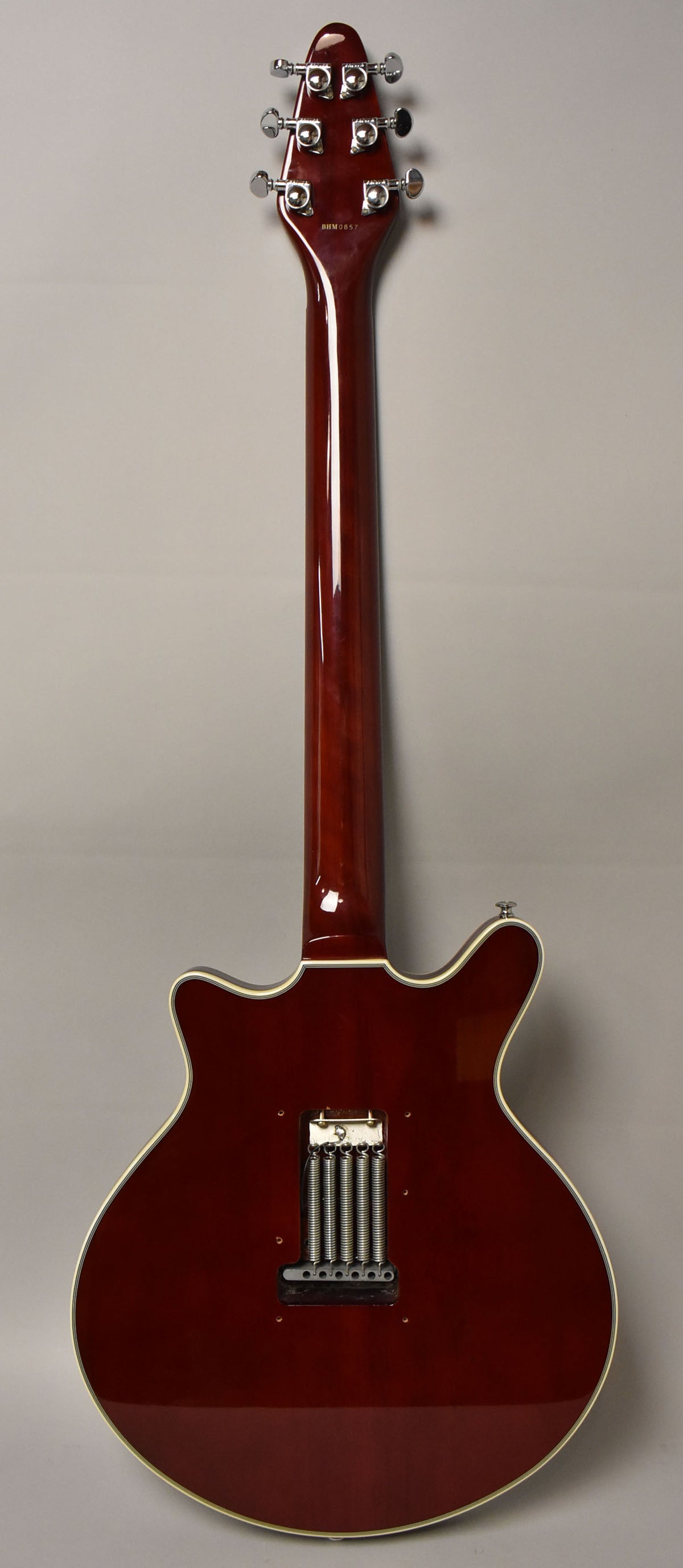 The guitar's cherry red back, neck, and headstock are visible, with a chrome tremolo system and six tuners.